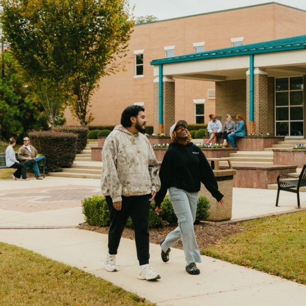 Two students chatting and laughing as they walk through the shamrock walkway by the Dublin Center